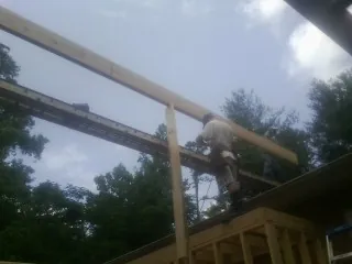 Carpenter setting a ridge beam over a new addition frame — Ice Dam Removal by Roofing Brothers in Pleasant Hill