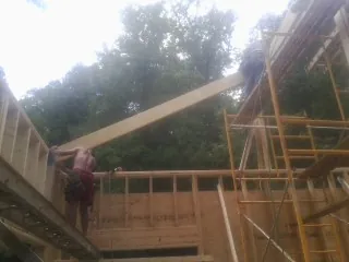 Carpenter raising a rafter beam on a new second story frame in Pleasant Hill